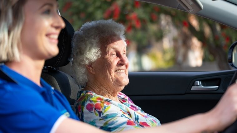 A smiling support worker in a car with a client