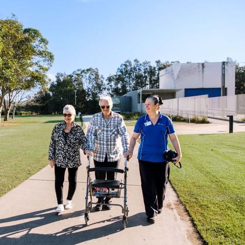 An older couple accompanied by a support worker on a walk