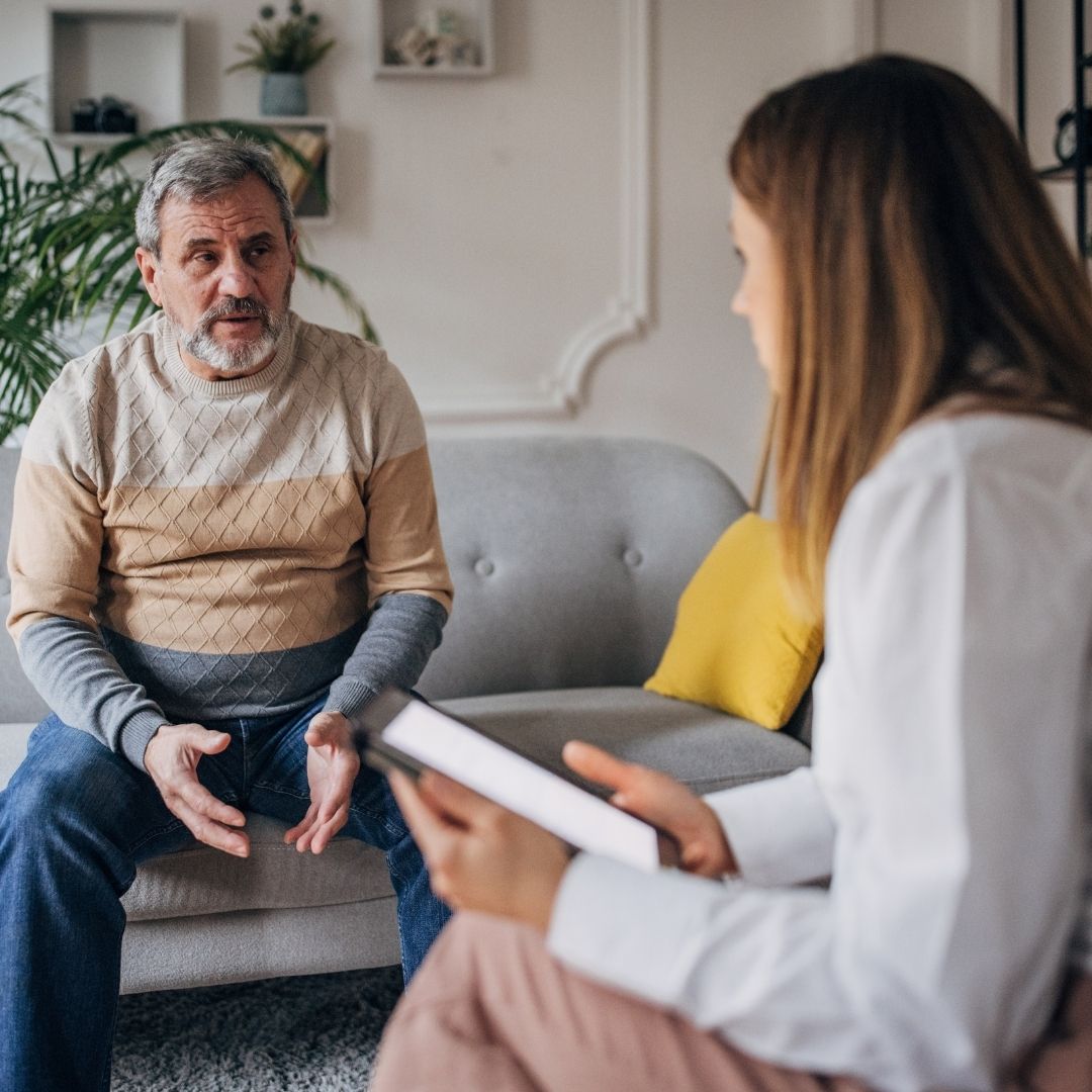 older man sitting on lounge talking with psychologist