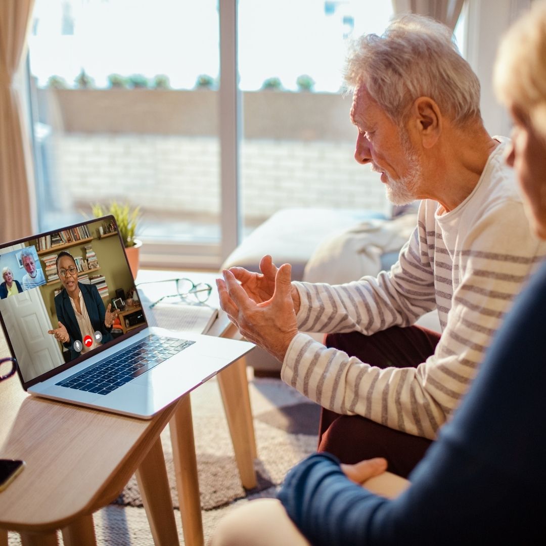 an elderly couple speaking with psychologist over video call on laptop