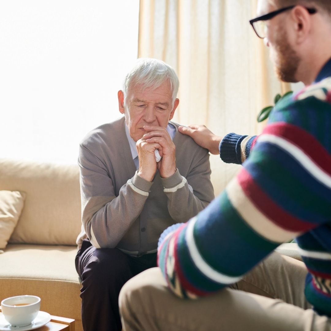 elderly man being consoled by a psychologist